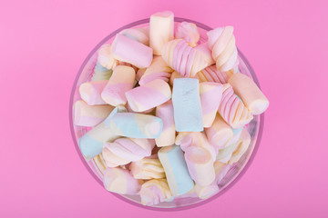 marshmallow candies of different colors in the glass on the background of pink. top view. entertainment for children in celebration.