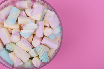 marshmallow candies of different colors in the glass on the background of pink. top view. entertainment for children in celebration.