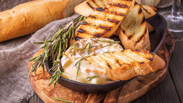 Homemade baked camembert with toasted bread and rosemary.