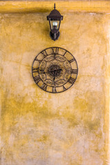 Vintage hanging  clock and lamp on old wall. Retro decoration for interior design.