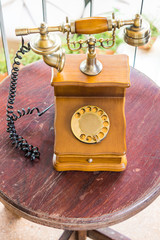 Vintage landline telephone on wooden table. It is a rotary dial phone.