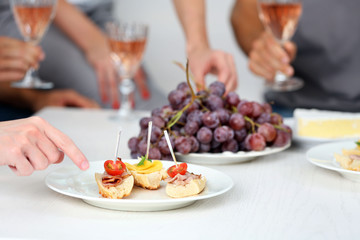 Obraz na płótnie Canvas Friends hands with glasses of wine and snacks, close up
