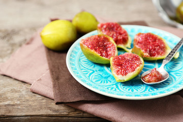 Ripe figs on plate, on wooden background