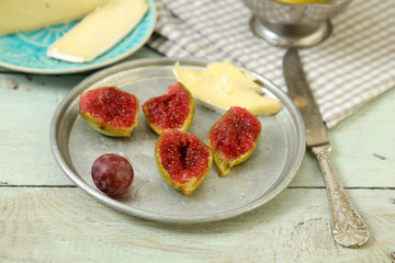 Ripe figs and cheese on tray, on wooden background