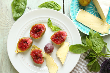 Ripe figs on plate, on color wooden background