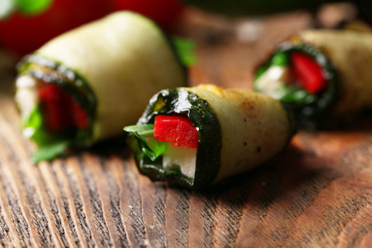Zucchini rolls with cheese, bell peppers and arugula, close-up
