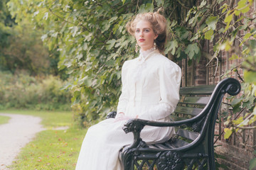 Posh victorian woman resting on garden seat.