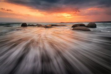 Sea sunrise. Stormy sea beach with slow shutter and waves flowing out