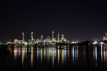 Fototapeta premium Light of oil refinery reflecting on the surface