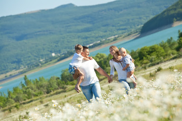 Happy family are walking in camomile field 