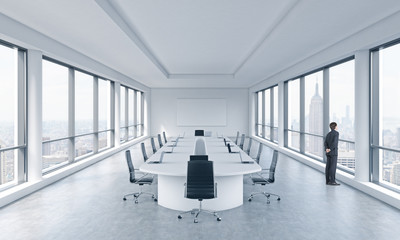 A Businessman is looking out the window in a modern panoramic meeting room in New York. The concept...