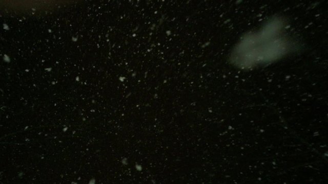 Snowing at night in the light of a lantern.