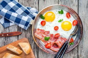 Breakfast with fried eggs, bacon, tomatoes and parsley