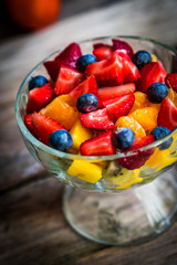 Colorful fruit salad in a jar on rustic wooden background