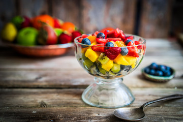 Colorful fruit salad in a jar on rustic wooden background