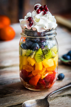 Colorful fruit salad in a jar on rustic wooden background