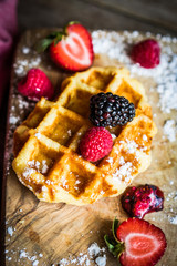 Belgian waffles with fresh berries on rustic wooden background
