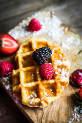 Belgian waffles with fresh berries on rustic wooden background