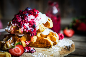 Belgian waffles with fresh berries on rustic wooden background