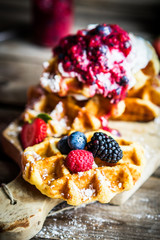 Belgian waffles with fresh berries on rustic wooden background