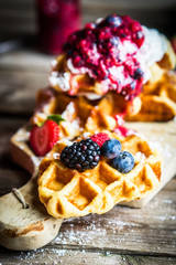 Belgian waffles with fresh berries on rustic wooden background