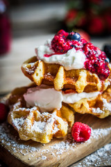 Belgian waffles with fresh berries on rustic wooden background