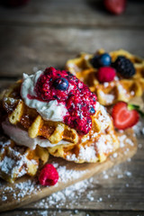 Belgian waffles with fresh berries on rustic wooden background
