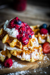 Belgian waffles with fresh berries on rustic wooden background
