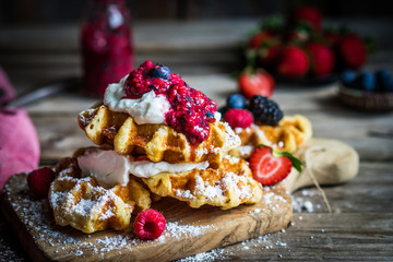 Belgian waffles with fresh berries on rustic wooden background