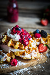 Belgian waffles with fresh berries on rustic wooden background
