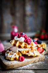 Belgian waffles with fresh berries on rustic wooden background