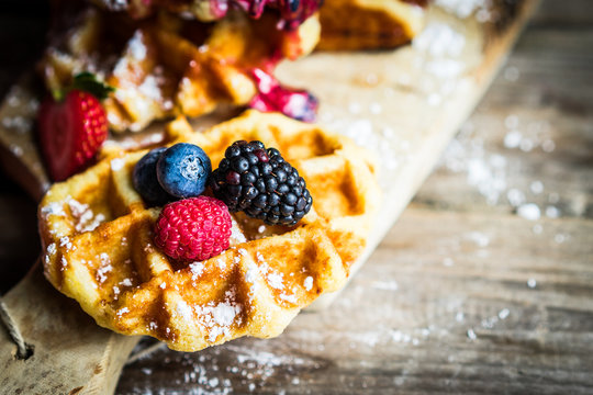 Belgian waffles with fresh berries on rustic wooden background