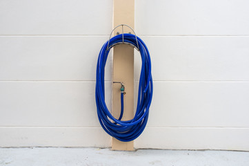 A blue rubber tube hanging on white wall