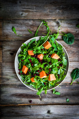 Fresh arugula and spinach salad with pumpkin on rustic backgroun
