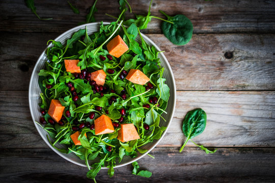 Fresh arugula and spinach salad with pumpkin on rustic backgroun