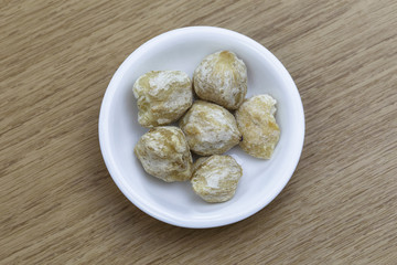 Dry candlenut in white bowl on wooden table