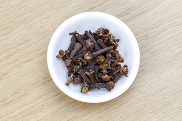Dry clove in white bowl on wooden table