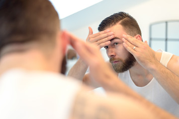 Mann mit Bart überprüft seine Haut