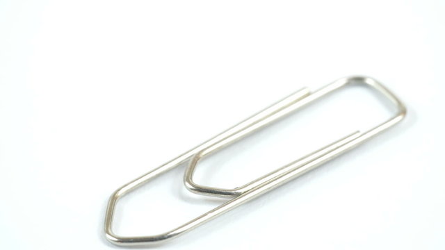 Silver metal paper clip on a table. This clip is used to bind the papers into one