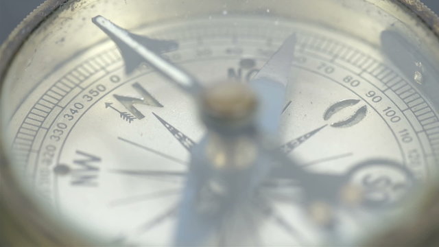 An old small round compass on a table. This old ancient compass is used for navigation and travel