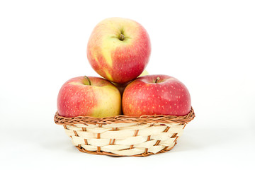 Красно-зеленые яблоки в корзинке на белом фоне