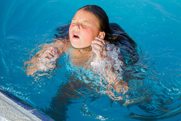 closeup view of little girl getting out from under water at swimming pool
