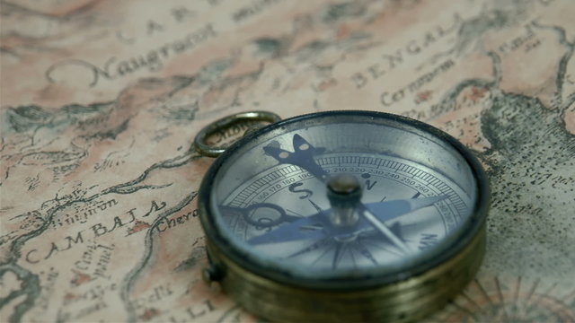 A round compass with its pointer moving pointing to some directions. 
