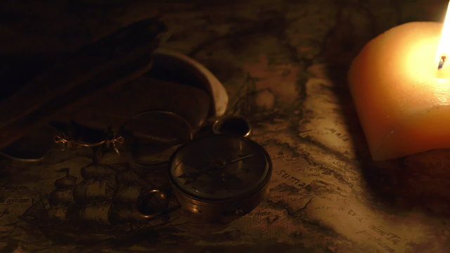 Navigators tools on top of a map. There are glasses ring and compass along with the candle to light up