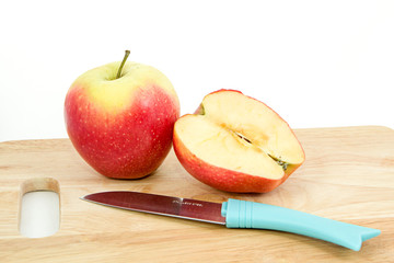 Красно-зеленые яблоки в корзинке на белом фоне на доске с ножом