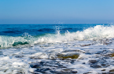 Waves breaking on a stony beach, forming sprays