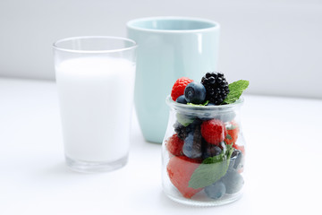 Berries with mint in jar and two glasses of milk