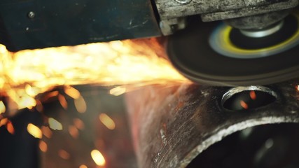 Metal worker grinding steel pipe, adult man using grinder to work on piece of metal in workshop, grinding sparks flying around, handheld camera with tracking focus - Powered by Adobe
