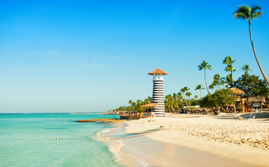 Paradise Caribbean landscape. Clear sea, white sand, tropical palm trees and lighthouse on sandy...