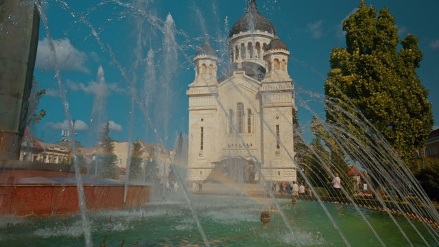 A close-up shot featuring the Dormition of the Theotokos Cathedral and water fountain in Cluj Napoca, Romania
